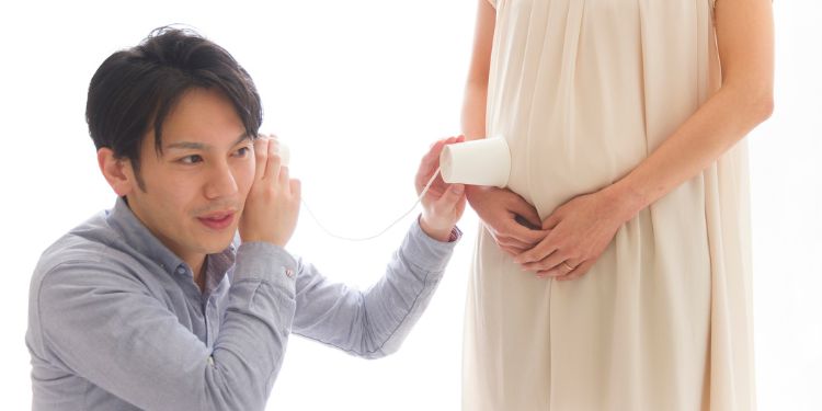 胎動を聞こうとする男性