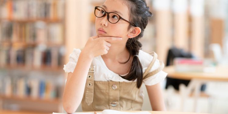 図書館でノートを開きながら考え事をしている女の子