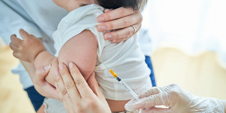 母親に抱かれ予防接種を受けている乳児