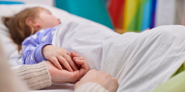 子どもの手を握り寝かしつける母親のイメージ