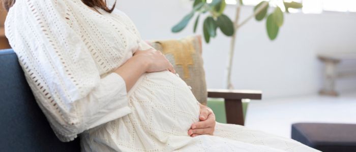 座りながらお腹をなでている妊婦