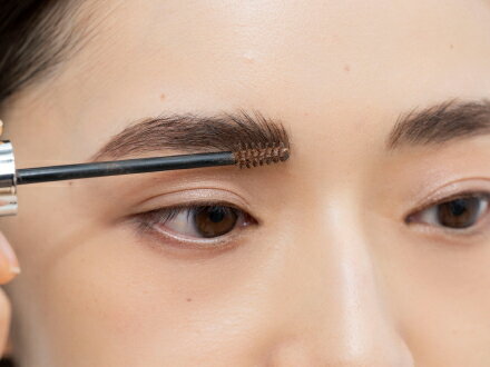 赤みブラウンの眉マスカラ③は、塗る前にブラシの液を軽くティッシュオフ。一度逆毛を立ててから毛流れに沿って整えると色づきが均一に。仕上げに眉山部分を上にとかして立体感をプラス。
